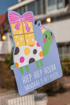 Raamsticker met kleurrijke felicitatie en feestschildpad voor verjaardagen of feestdagen.