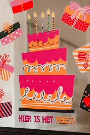 Roze/Oranje Raamsticker in de vorm van een taart met 'Hier is het feest!' tekst.