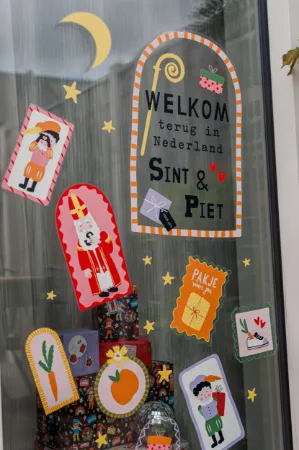 Raamsticker met vrolijke Sinterklaas- en Piet-illustraties.